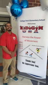 Coach standing by a KiDsGyM USA banner